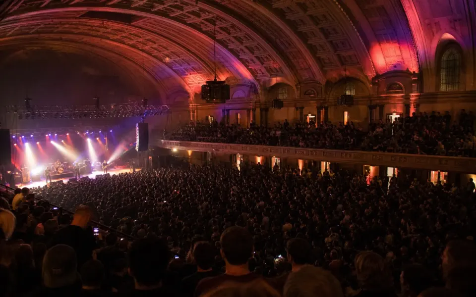 Illustration: a rock concert inside a large historic arena, seen from an upper balcony