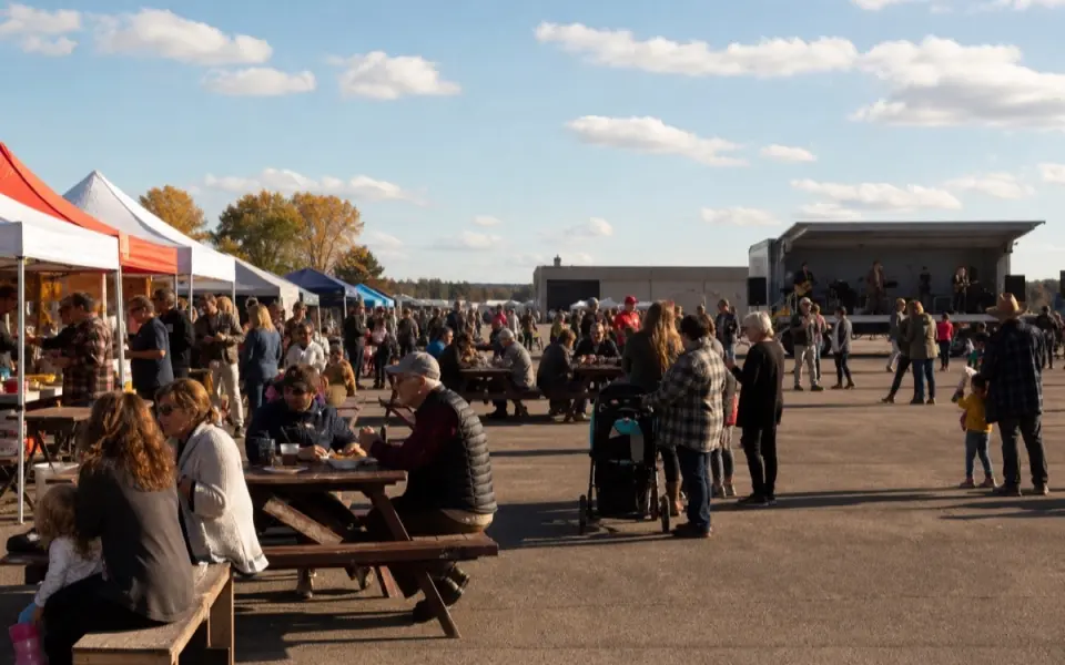 Illustration: an outdoor food and music festival with canopy stalls and families at picnic tables